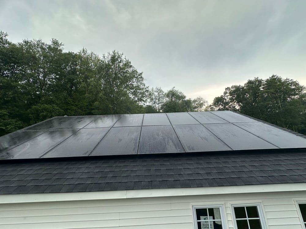 aerial view of a residential roof installation with solar panels and workers on the job